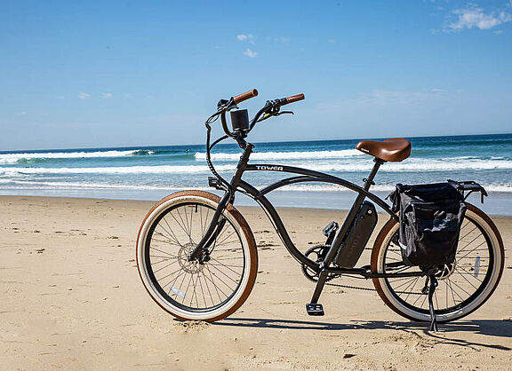 Ein stylishes Fahrrad steht am Strand, an den Wellen schlagen