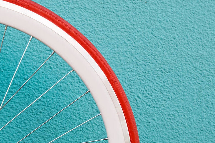 Die Farben kommen wieder Ausschnitt eines Laufrades mit rotem Mantel vor türkisfarbener Wand