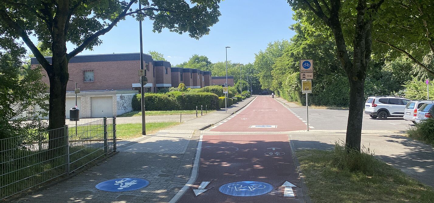 Rot gefärbter Radweg mit einer rot gefärbten Fahrradstraße im Hintergrund