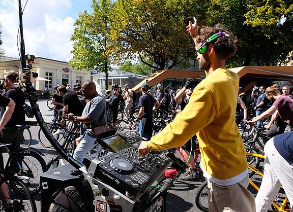 Ein Mann mit Kopfhörern bedient ein Musikpult, das an einem Fahrrad angebracht ist