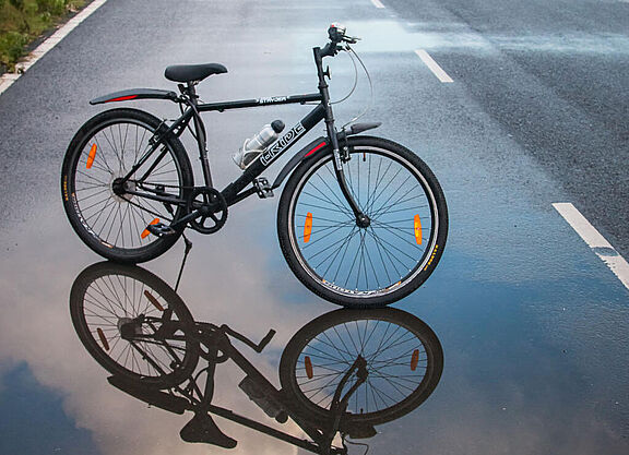 Ein Fahrrad spiegelt sich in der Pfütze einer Straße