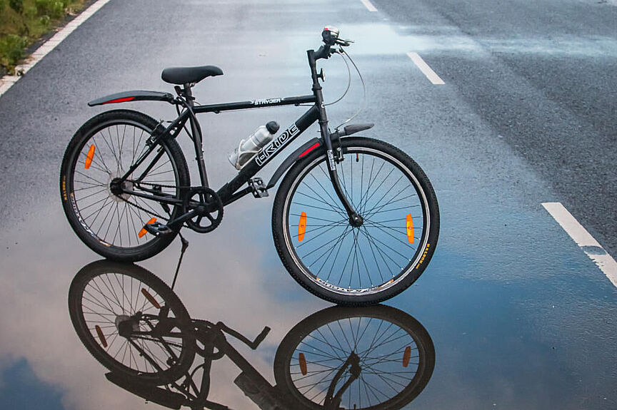 Nass aber schön Ein Fahrrad spiegelt sich in der Pfütze einer Straße