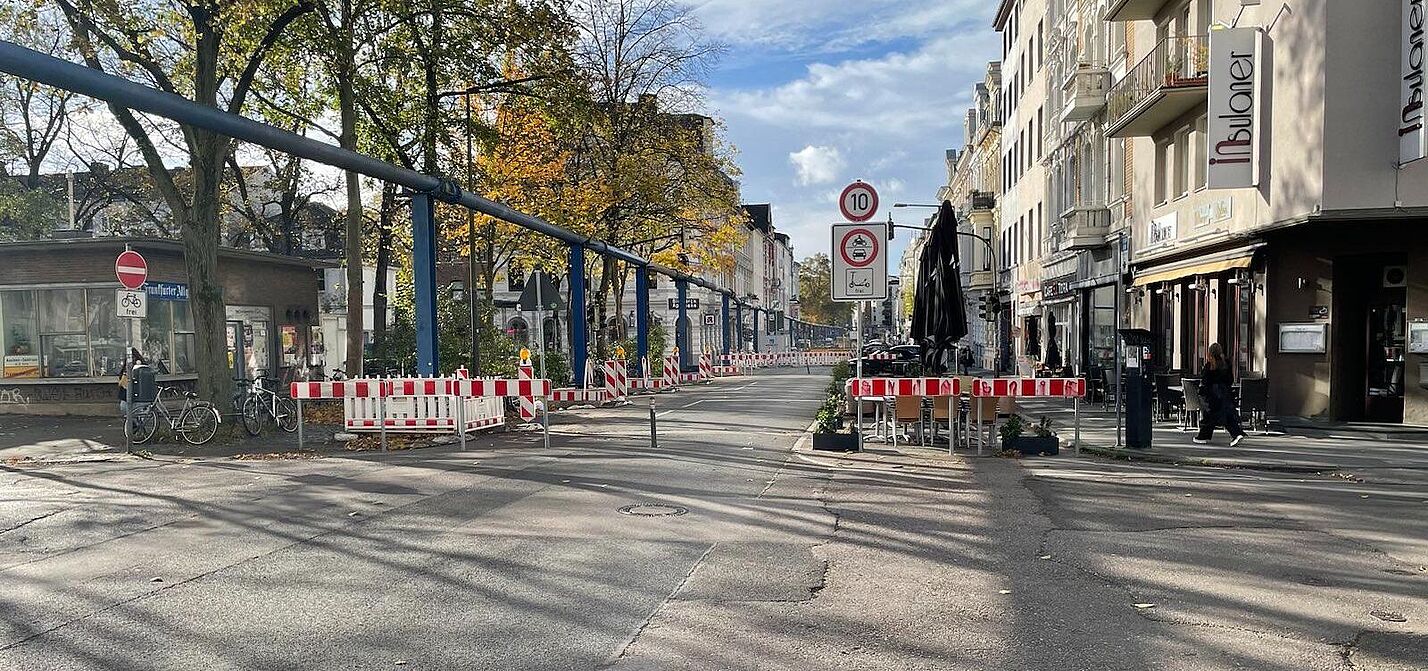 Die Bismarckstraße auf Höhe des Modalfilters am Neumarkt. Es sind zwei Poller und Warnbaken aufgestellt