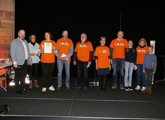 Zehn Personen stehen auf einer Bühne, davon sechs in ADFC-T-Shirts