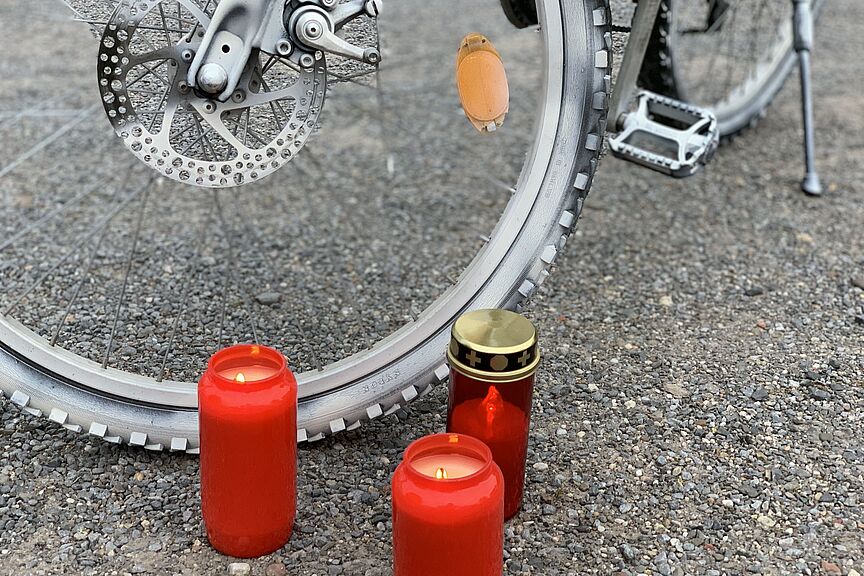 Ein weißes Ghostbike und brennende Kerzen. Ein weißes Ghostbike und brennende Kerzen.